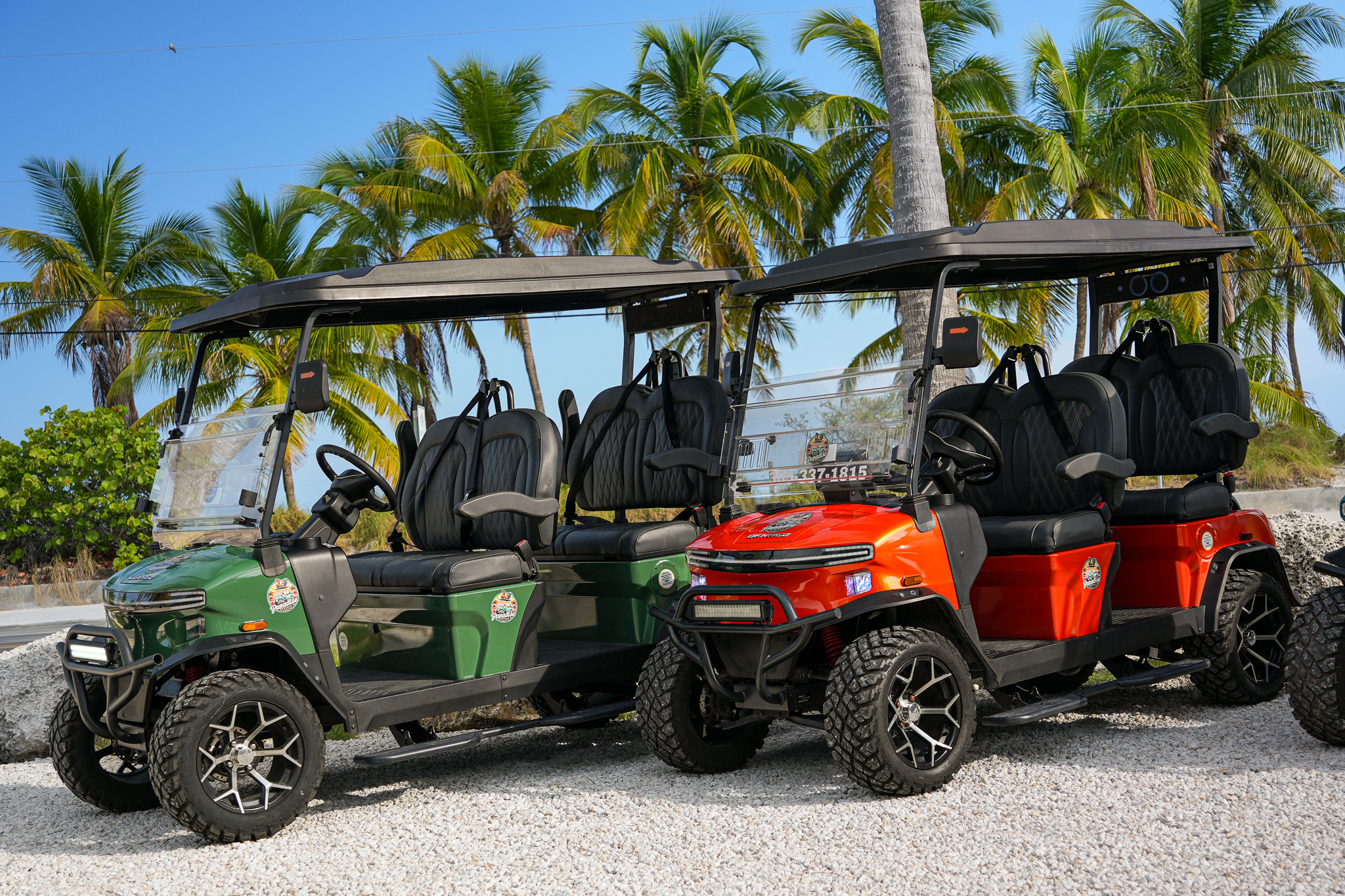 Green and orange golf carts on gravel